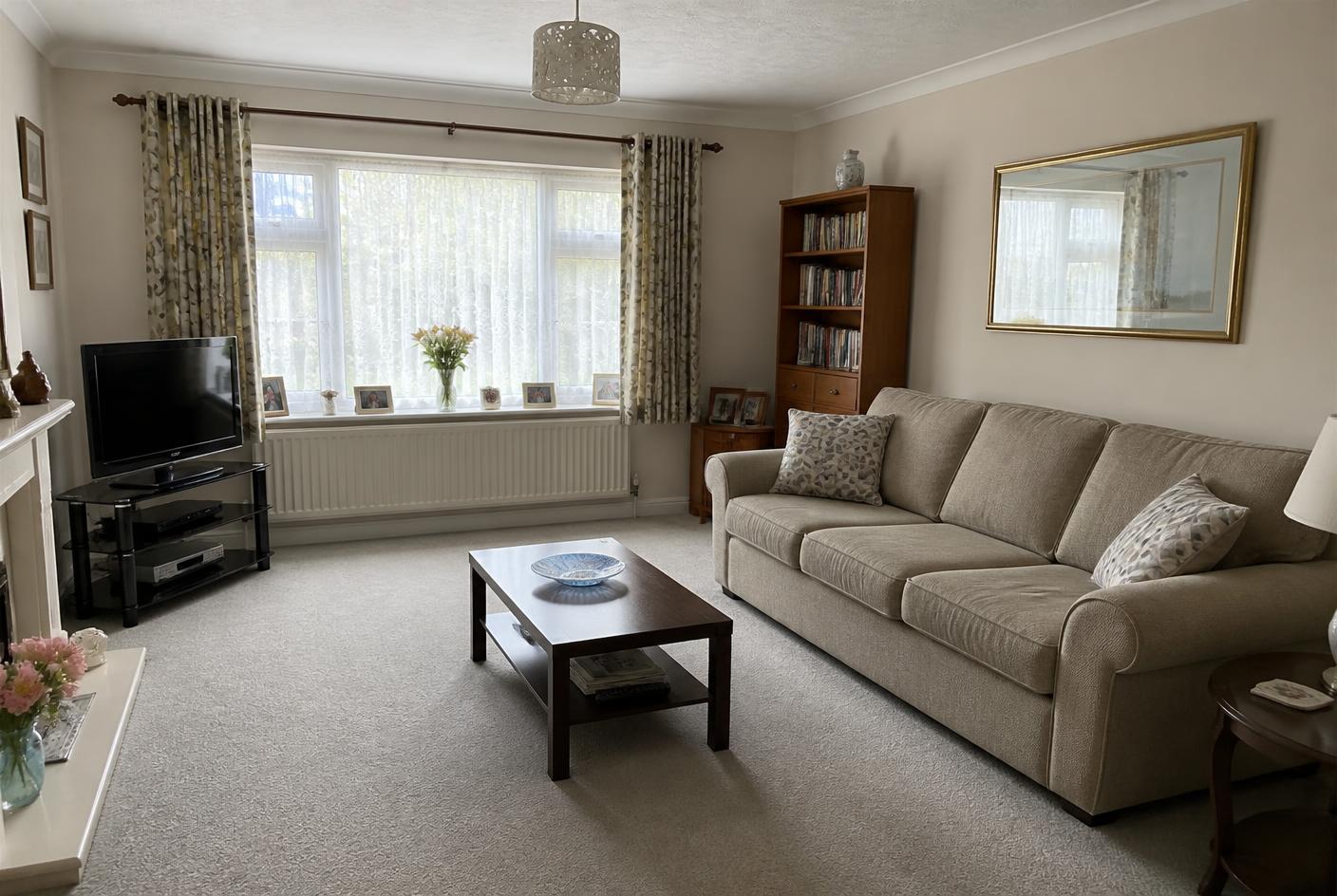 The same living room tidied, with straightened cushions, a clear table and vacuumed carpet